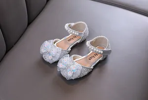 Detail view of silver sparkling girls princess shoes with rhinestone butterfly bows and pearls.