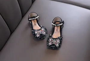 Detailed view of girls' black princess shoes with rhinestone butterfly and pearls.