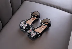 Detail view of black girls princess shoes with butterfly rhinestone bow and pearl strap