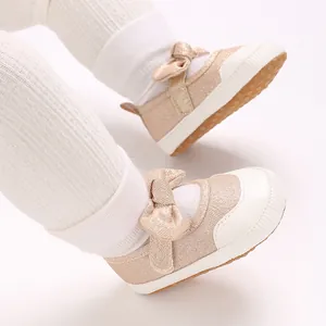 Close-up of pink glitter baby walking shoes with a delicate bow and soft white sole.