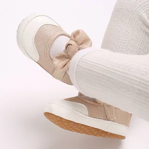 Close-up of pink glittery baby walking shoes with bow detail and anti-slip sole.