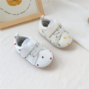 Detail van baby loopschoentjes met zachte zool en borduursels van hart en dinosaurus.