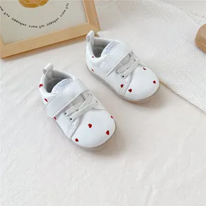 Gedetailleerd overzicht van witte baby loopschoentjes met schattige rode hartjes