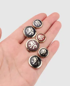 Close-up detail of luxury metal buttons featuring an embossed gold lion crest on a hand.