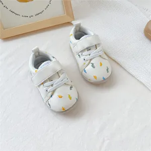 Crèmekleurige babyloopschoenen met kleurrijke dinosauruspatronen op een witte ondergrond