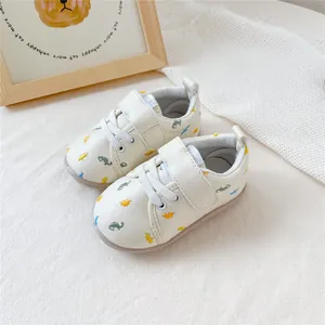 Detailweergave van witte baby-loopschoenen met kleurrijke dinosaurusborduursels en klittenband