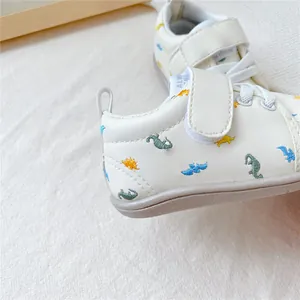 Detailopname van beige babyloopschoentjes met schattige kleurrijke dinosaurusborduurwerk