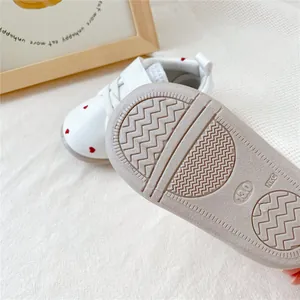 Detailopname van de antislipzool van witte babyloopschoentjes met een hartjespatroon.