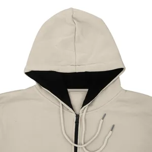 Close-up detail of a beige men's hooded fleece sweatshirt with black lining and drawstring.