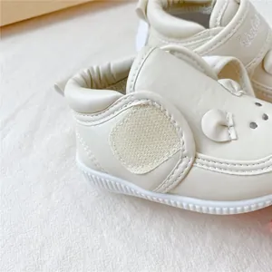 Gros plan de chaussures de marche pour bébé à semelle souple crème avec design mignon
