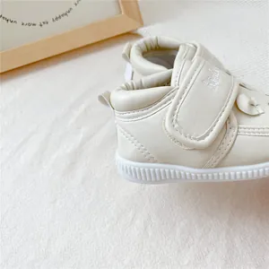 Vue rapprochée de chaussures de marche pour bébé crème avec semelle souple et velcro