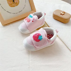Close-up of pink baby walking shoes with embroidered strawberry and cherry patches