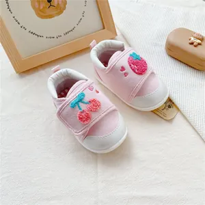Detailed macro view of pink baby walking shoes featuring cute fruit embroidery details