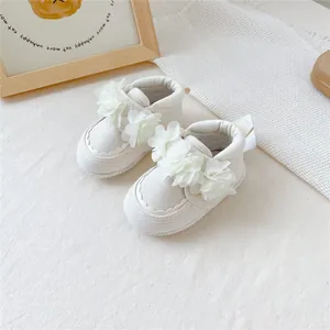 Détail de chaussures de marche souples pour bébé blanches avec fleurs en tissu