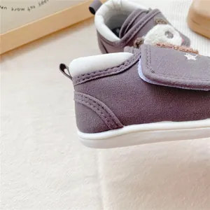 Close-up detail of soft-soled baby walking shoes with cartoon bear design