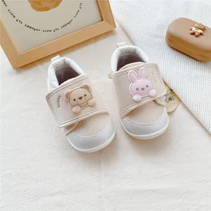 Detail of cute cartoon baby walking shoes with soft soles, velcro strap, beige canvas.