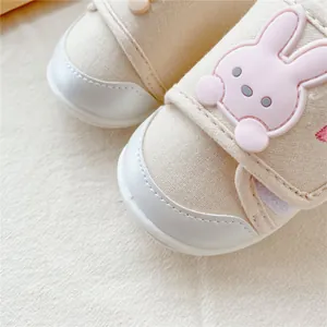 Macro detail of a cute pink cartoon bunny on beige baby soft sole walking shoes