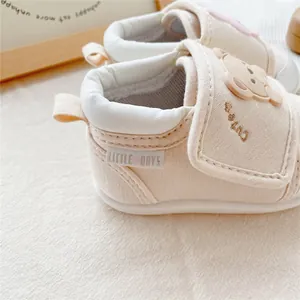 Close-up of beige baby walking shoes featuring a cute bear patch and soft sole.