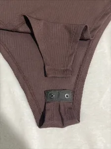 Close-up detail of the snap button closure on a brown ribbed knit fabric bodysuit