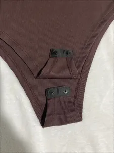 Detail shot of brown ribbed bodysuit featuring functional snap-button closure at crotch.