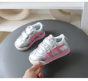 Detailansicht silberner Kinderschuhe mit rosa Streifen und doppeltem Klettverschluss