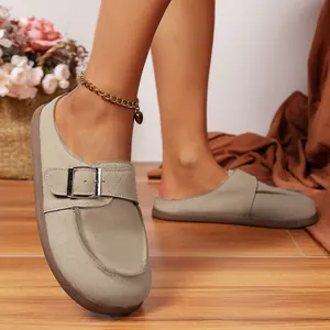 Élégantes mules rétro en daim à bout rond avec boucle decorative sur un sol en bois naturel