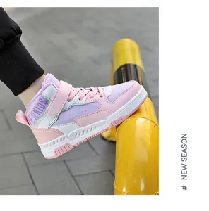Un primo piano di sneakers alte da bambino rosa e viola su una ringhiera gialla
