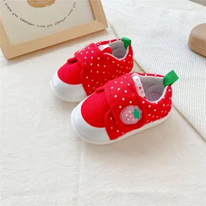 Gedetailleerd overzicht van rode baby meisjes loopschoenen met stippen en aardbeipatch.