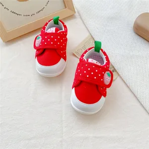 Detailopname van rode babyschoentjes voor meisjes met aardbeienpatroon en klittenband