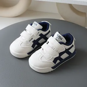 Weiße und marineblaue Kinder-Sneaker im German Trainer-Stil mit Klettverschluss.
