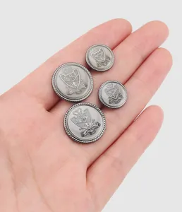 Gros plan de boutons en métal en alliage de zinc avec blason présentés sur une paume
