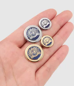 Detail showing blue enamel crest buttons in gold and silver held in a human hand.
