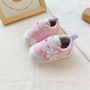 Detail van roze baby-loopschoentjes met witte madeliefje versiering en klittenbandsluiting