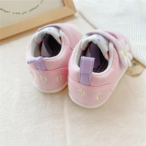 Detail van zachte babyloopschoenen voor meisjes met roze madeliefjes en klittenbandsluiting