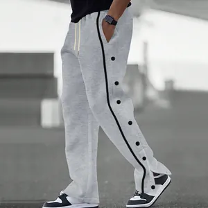 Dettaglio bottoni automatici laterali su pantaloni larghi grigi da uomo con coulisse
