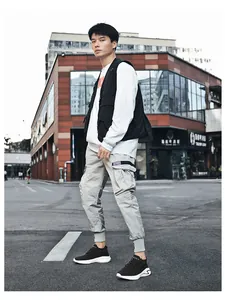 Fashionable man in urban street wearing black breathable knit sneakers with white sole.