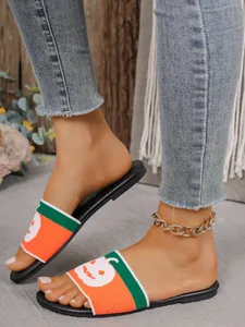 Detalle de chanclas planas para mujer con tira de punto con diseño de calabaza naranja.