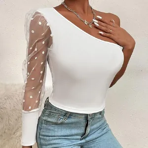 Détail du haut blanc à une épaule avec une élégante manche en mesh transparente à pois