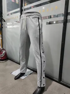 Dettaglio dei pantaloni sportivi grigi da uomo con dei bottoni a pressione laterali