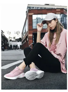 Macro view of pink breathable flyknit athletic sneakers worn by model on urban street