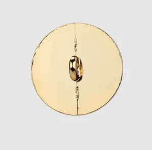 Detail macro view of a circular gold metal button featuring a sturdy shank back for sewing