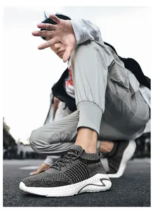 Close-up of grey breathable knit sneakers worn by a model in an urban street setting