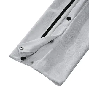 Dettaglio ravvicinato dei bottoni a pressione laterali su pantaloni da uomo.