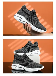 Close-up of grey breathable fly-knit sneakers with white textured soles in studio