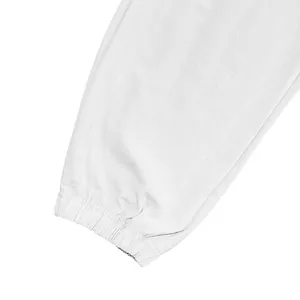 Macro detail showing the elasticized ankle cuff of white cotton linen jogger pants.