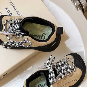 Toddler walking sneakers with soft soles, beige suede uppers, and checkered laces.