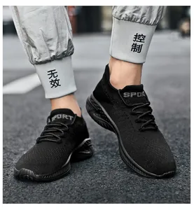 Detail view of black breathable knit sneakers for men and women on a street surface.