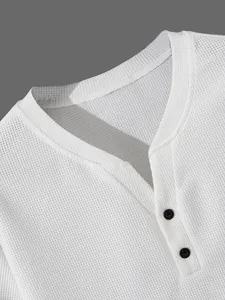 Nahaufnahme eines weißen Henley-Shirts aus Waffelstrick mit schwarzen Knöpfen und Textur.