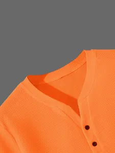 Detailansicht eines leuchtend orangefarbenen Henley-Shirts mit Waffelstrick und Knöpfen