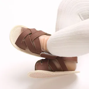 Detalle de sandalias para bebé en cuero PU marrón con suelas blandas en pies